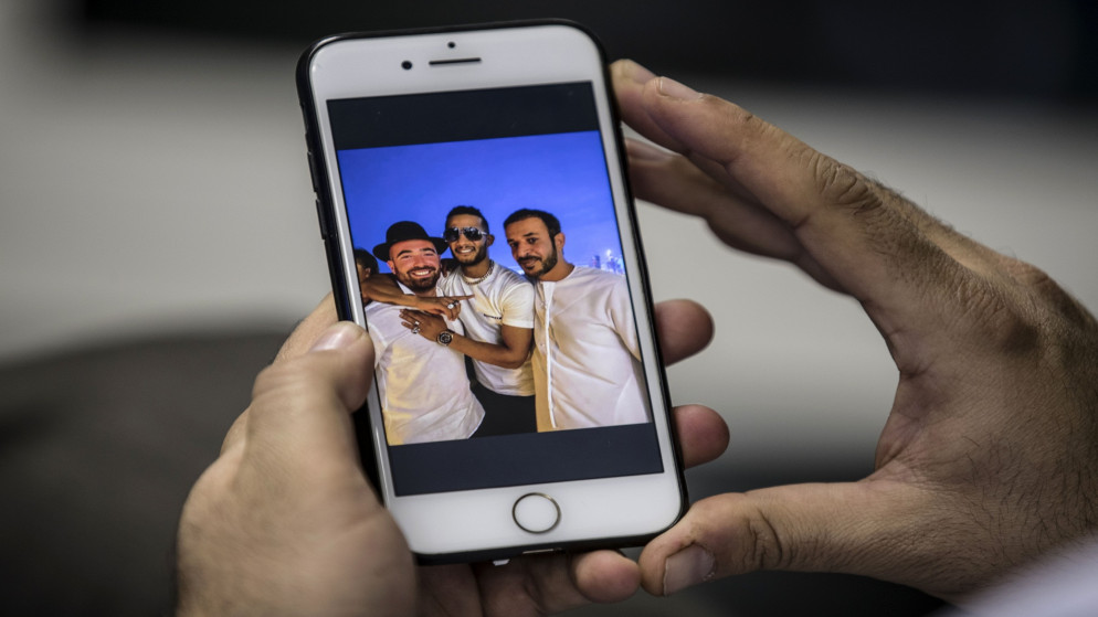 رجلاً يحمل هاتفًا يعرض صورة الممثل المصري محمد رمضان (وسط) يعانق مطرب إسرائيلي عمر آدم (اليسار)، ممثل ومغني راب. 22 نوفمبر 2020. (أ ف ب)