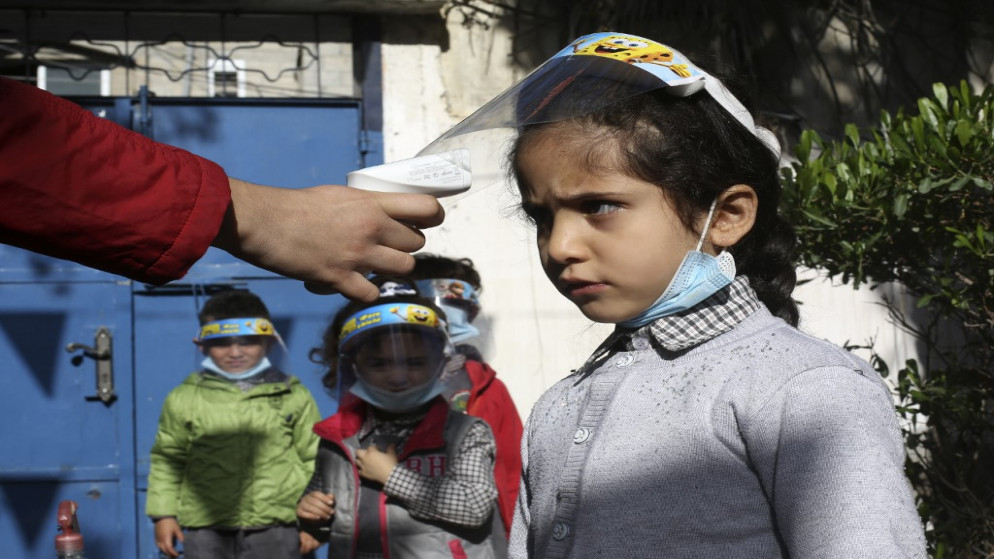 فحص درجة حرارة أطفال فلسطينيين عند وصولهم إلى روضة أطفال في قطاع غزة وهم يرتدون دروعًا واقية للوجه؛ بسبب كوفيد-19. 23/11/2020, (محمد عابد / أ ف ب)