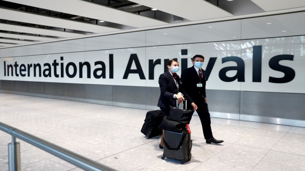 أفراد طاقم رحلة الخطوط الجوية البريطانية يرتدون كمامات واقية للوجه عند وصولهم إلى المبنى رقم 5 في مطار هيثرو غربي لندن. 08/06/2020. (أدريان دينيس / أ ف ب)