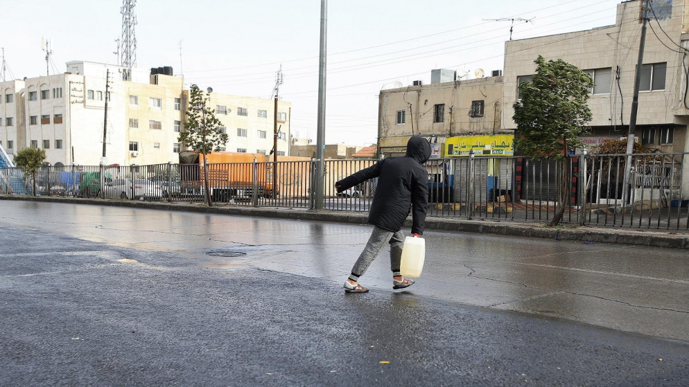 صورة أرشيفية لشخص يحمل "غالون" كاز تزامنا مع المنخفض الجوي في ماركا الشمالية في عمّان، 26/12/2019. (صلاح ملكاوي / المملكة)