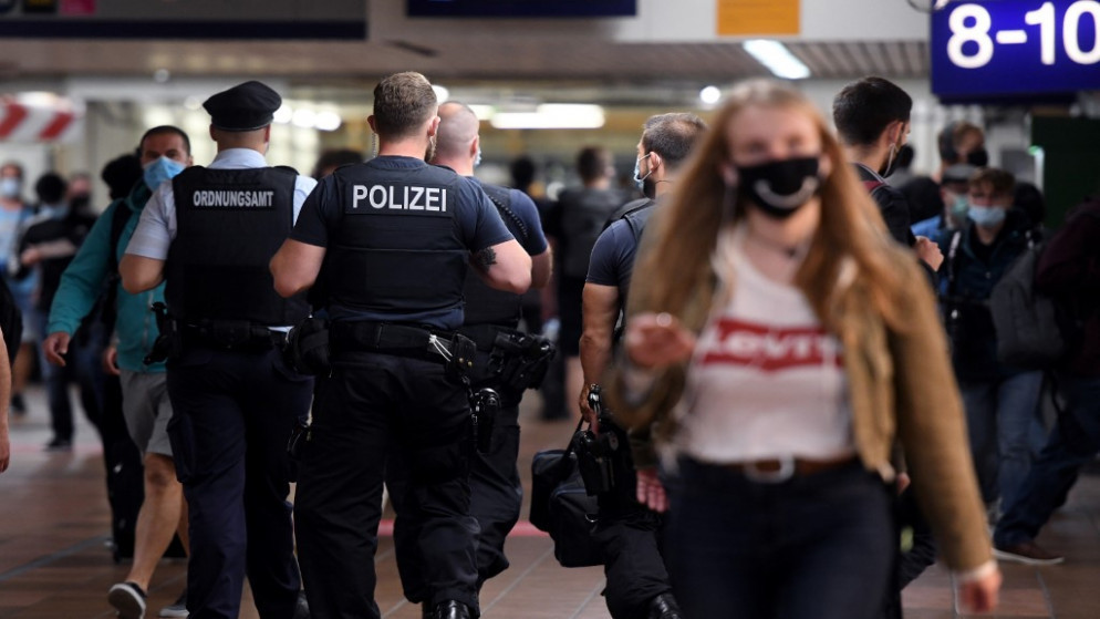 يقوم موظفو مكتب النظام العام، بإجراء عمليات التفتيش لضمان ارتداء الكمامة، وسط جائحة كورونا، محطة السكك الحديدية الرئيسية في دورتموند، غرب ألمانيا (أ ف ب)