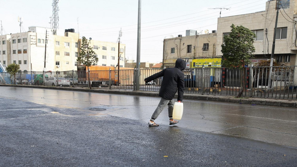 شخص يحمل "غالون" كاز تزامنا مع المنخفض الجوي في ماركا الشمالية في عمّان، 26/12/2019. (صلاح ملكاوي / المملكة)