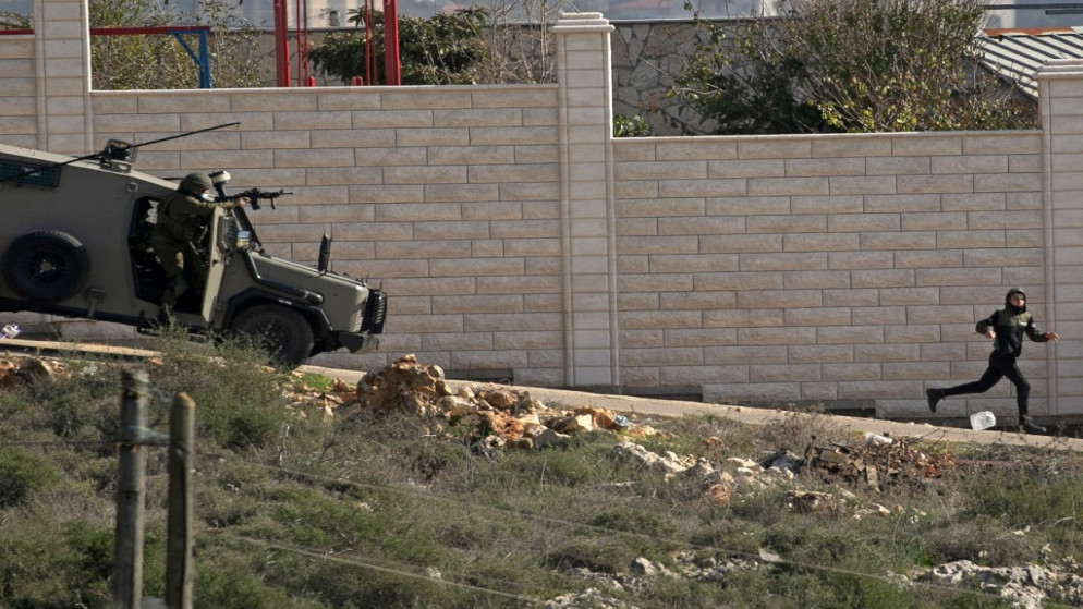 طفل فلسطيني يحاول الهروب من مركبة لجنود الاحتلال الإسرائيلي خلال مواجهات في الضفة الغربية المحتلة. (أ ف ب)