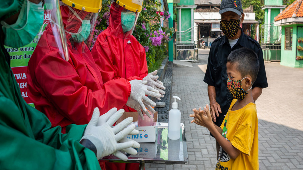 العاملون الصحيون يشرحون طريقة غسل اليدين بشكل صحيح لطفل في مركز صحي مجتمعي في وسط جافا، بإندونيسيا. (يونيسف)