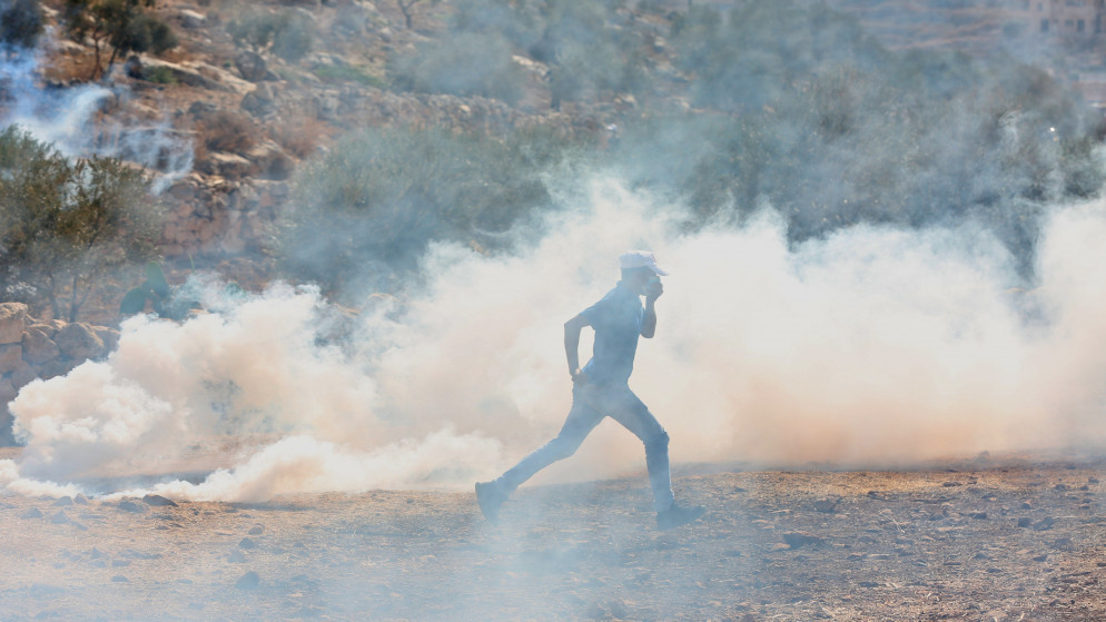 فلسطيني يرتدي كمامة للوقاية من كوفيد-19 خلال مواجهات مع جنود الاحتلال الإسرائيلي خلال مسيرة سلمية ضد التوسع الاستيطاني في قرية بيت دجن شرق مدينة نابلس. 2020/10/30. (أيمن نوباني/ وفا)