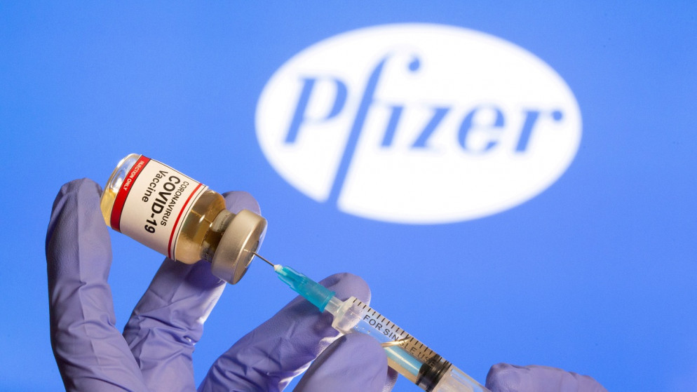 زجاجة صغيرة عليها ملصق "لقاح فيروس كورونا COVID-19" وحقنة طبية أمام شعار شركة فايزر، 10/12/2020. (رويترز)