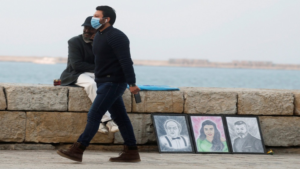 رجل يرتدي كمامة ويسير أمام رسومات في مدينة الإسكندرية على البحر المتوسط ​في مصر، 6 كانون الأول/ديسمبر 2020. (رويترز)