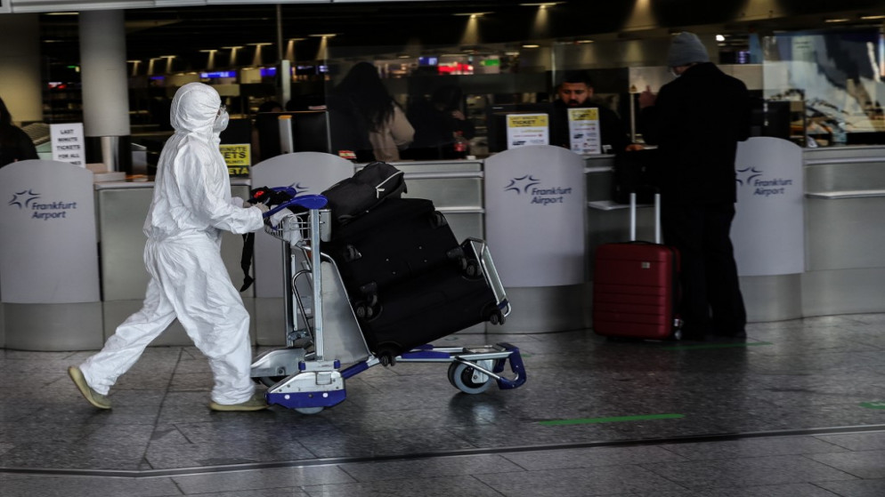 مسافر يرتدي بدلة واقية ويدفع عربة أمتعة في مطار فرانكفورت الدولي في فرانكفورت غرب ألمانيا، 19 كانون الأول/ديسمبر 2020 (أ ف ب)