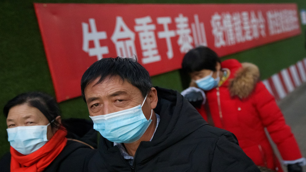 أشخاص يرتدون الكمامات في شارع عام في العاصمة بكين. (رويترز)