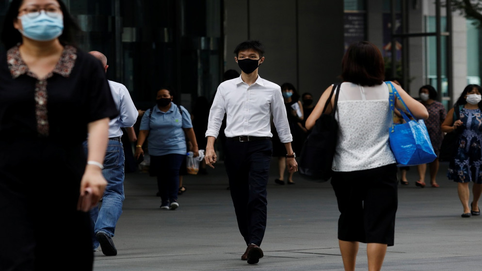 أشخاص يرتدون كمامات واقية كإجراء احترازي ضد مرض الفيروس، يمشون في الحي التجاري المركزي في سنغافورة، 14 كانون الأول/ ديسمبر 2020. (رويترز)