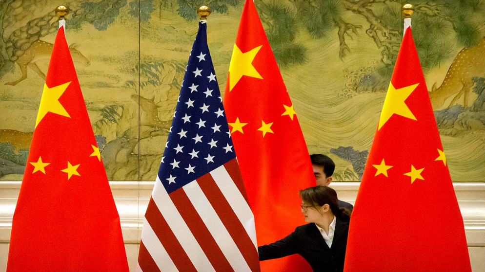 موظفون صينيون يعدلون الأعلام الأميركية والصينية قبل الجلسة الافتتاحية للمفاوضات التجارية الصينية الأميركية في بكين، 14 فبراير 2019. (رويترز)