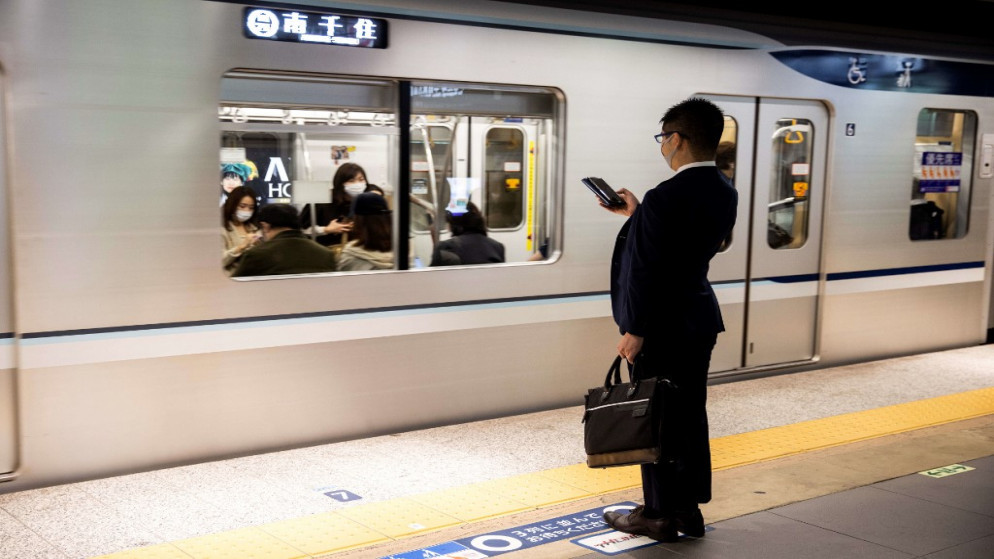 راكب يرتدي قناع وجه يفحص هاتفه في محطة جينزا في طوكيو في 19 تشرين الثاني/نوفمبر 2020. (أ ف ب)