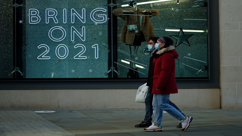 أشخاص يمشون أمام لافتة في نافذة متجر وسط تفشي فيروس كورونا في مانشستر، بريطانيا، 15 كانون الأول/ديسمبر 2020. (رويترز / فيل نوبل)