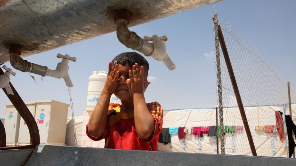 طفل يغسل وجهه بالماء من صنابير مياه في مخيم للاجئين السوريين في منطقة الزعتري في محافظة المفرق شمالي الأردن. (صلاح ملكاوي/ المملكة)