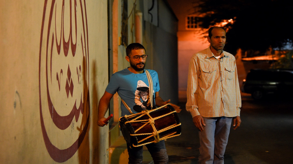 رجلان يعملون بمهنة "مسحراتي" يسيران في الشوارع لإيقاظ المسلمين لتناول وجبة السحور خلال شهر رمضان في العاصمة البحرينية المنامة. 10/05/2020. (مازن مهدي / أ ف ب)