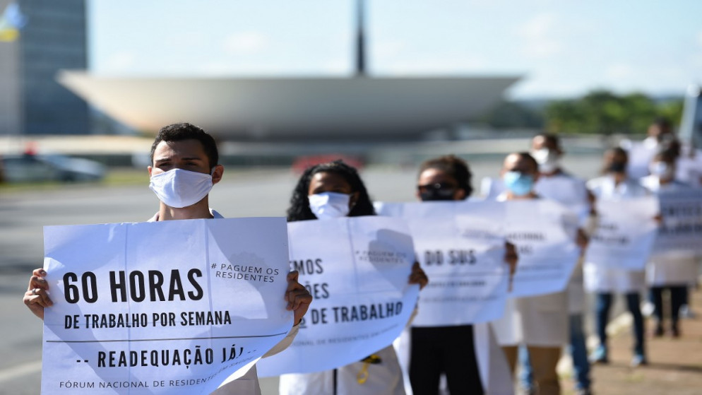 يحتج عاملون صحيون، على ظروف العمل والتأخير في الأجور أمام وزارة الصحة في برازيليا، 21 مايو 2020. (أ ف ب)