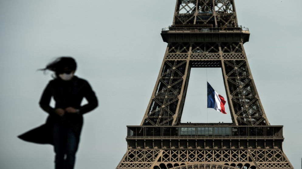امرأة ترتدي قناعاً واقياً أمام برج إيفل في باريس، 11 أيار/مايو 2020. (أ ف ب)