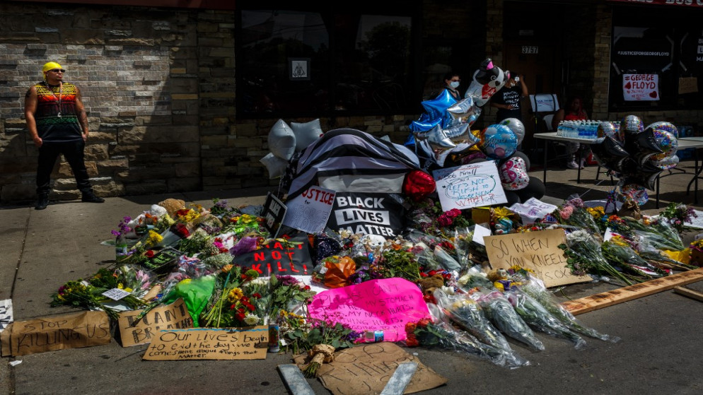 زهور ولافتات عند نصب تذكاري مؤقت لجورج فلويد بالقرب من المكان الذي توفي فيه أثناء احتجازه . 27 مايو 2020. (كيرم يوسل / أ ف ب)