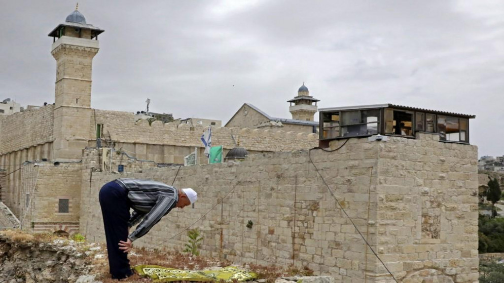 فلسطيني يصلي على سطح منزله أمام المسجد الإبراهيمي في مدينة الخليل في الضفة الغربية المحتلة، 24 أبريل/نيسان 2020. (حازم بدر/ أ ف ب)