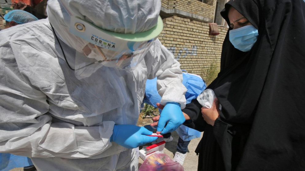 مسعف عراقي يأخذ عينة من سيدة خلال حملة جمع عينات لفحص فيروس كورونا في مدينة الصدر العراقية. 21/05/2020. (أحمد الربيعي / أ ف ب)
