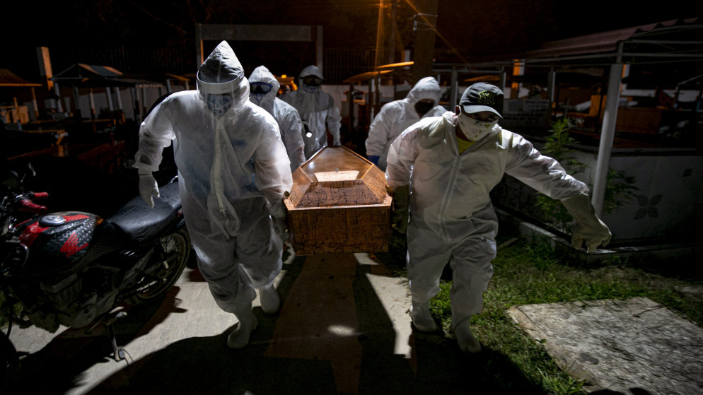 حفارو القبور يرتدون ملابس واقية يحملون نعش ضحية فيروس كورونا لدفنها. البرازيل. 30 مايو 2020. (أ ف ب)