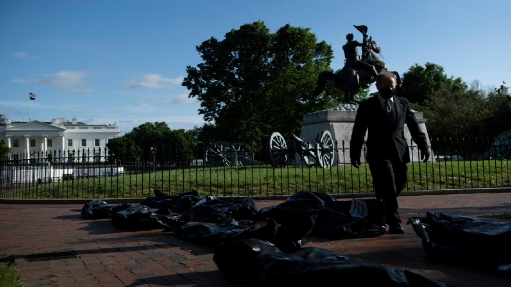 ناشط يسير وسط أكياس تستخدم للفّ الجثث وضعت أمام البيت الأبيض في واشنطن، 20 ايار/مايو 2020. (أ ف ب)
