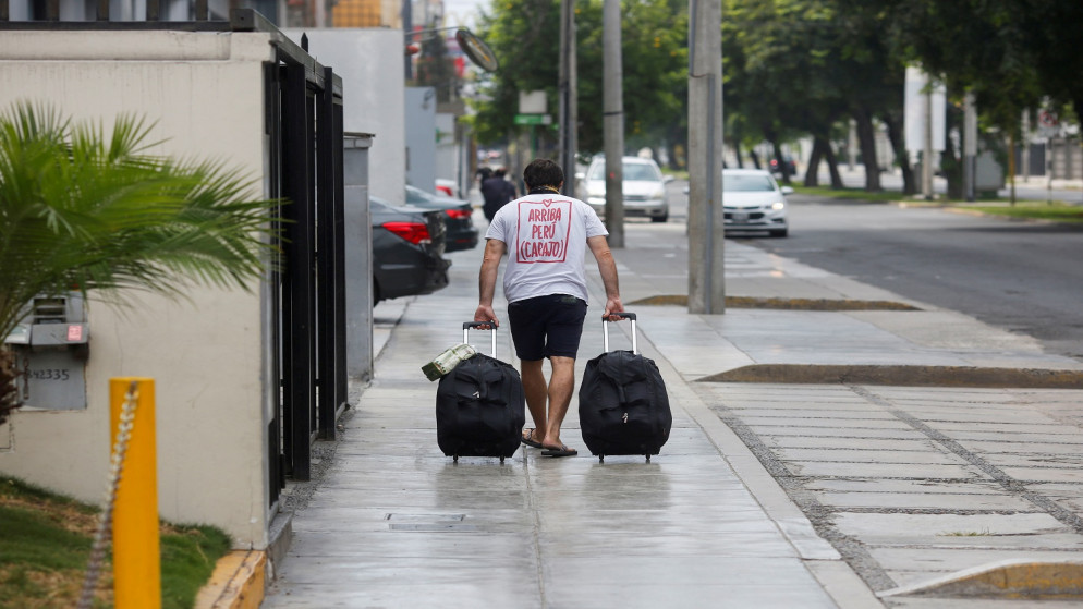 رجل يسير مع حقائبه على رصيف بعد أن حدّدت الحكومة البيروفية أيام مغادرة المنازل . بيرو 3 أبريل 2020. (رويترز)