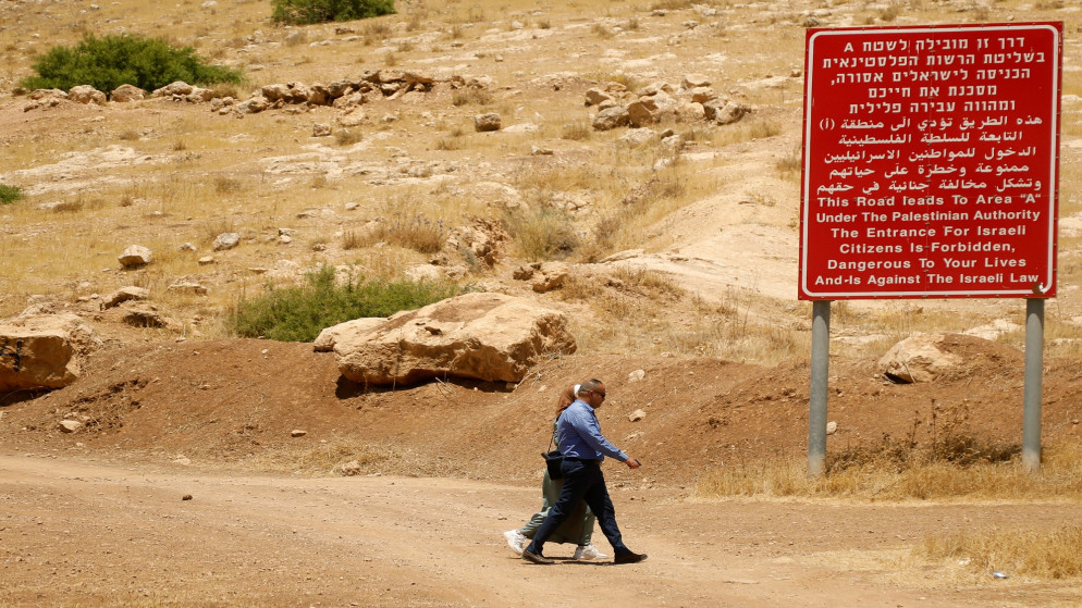 فلسطينيون يسيريون أمام لافتة توضح معلومات عن المنطقة "أ" في غور الأردن بالضفة الغربية المحتلة. 13/06/2020. (رنين صوافطة/ رويترز)
