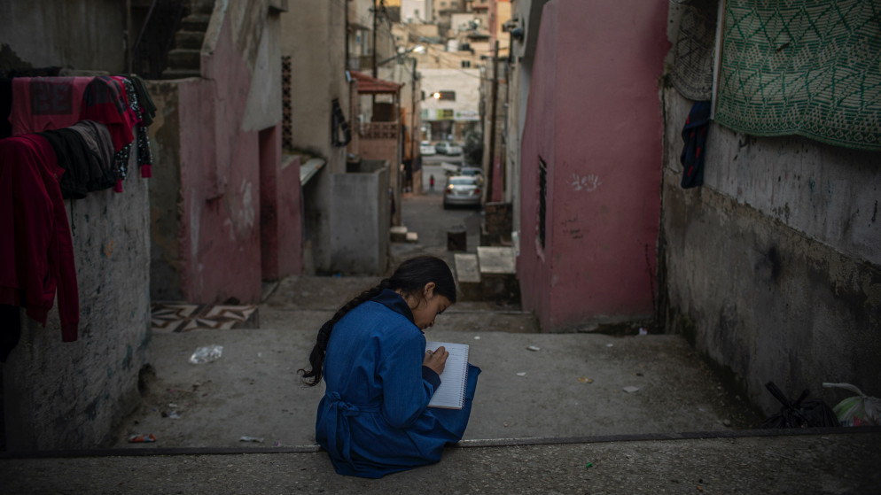 طفلة سورية تقرأ كتاب في أحد أحياء العاصمة عمّان. (دييغو إيبارا سانشيز/ مفوضية الأمم المتحدة لشؤون اللاجئين)