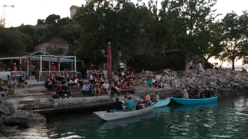موسيقيون إيطاليون على شاطئ بحيرة في إيطاليا يعزفون ألحانهم من فوق حيث قوارب الصيد. 21 يونيو ، 2020. (رويترز)