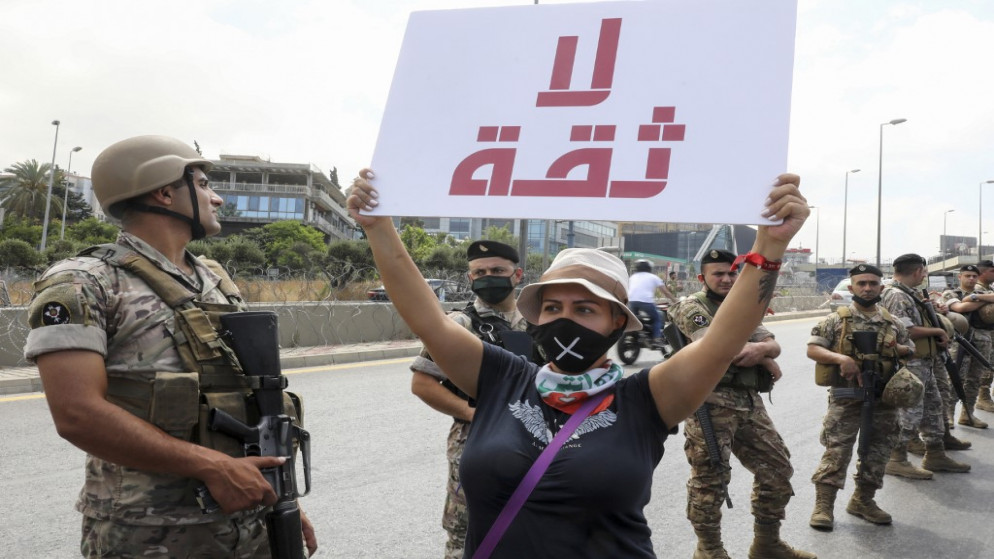 متظاهرة لبنانية تحمل لافتة مكتوب عليها "لا ثقة" أمام جنود الجيش اللبناني . بيروت.25 يونيو 2020. (أنور عمرو / أ ف ب)