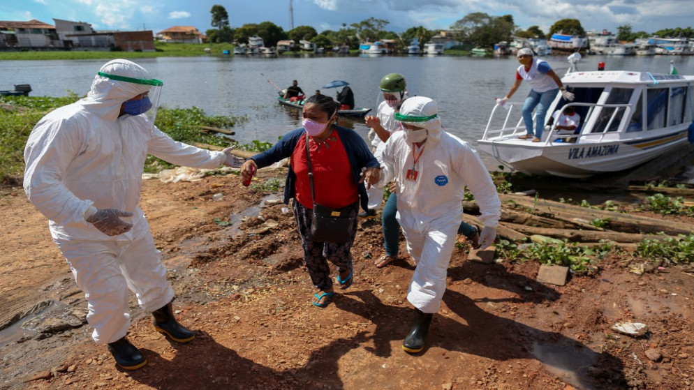 يساعد المهنيون الصحيون المرضى الذين يعانون من أعراض الفيروس، تم إحضارهم بالقارب من مجتمع فيلا أمازونيا عند وصولهم إلى بارينتينس، ولاية أمازوناس، البرازيل، 27 يونيو 2020. (أ ف ب)