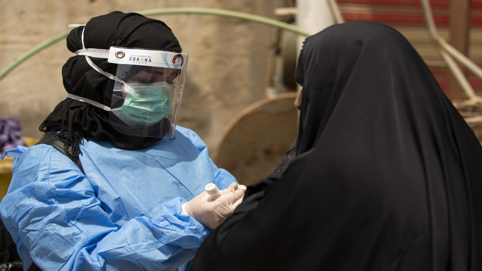 ممرضة تستعد لأخذ مسحة فحص من امرأة للتأكد من عدم إصابتها بفيروس كورونا المستجد في جنوب البصرة العراقية. 02/06/2020. (حسين فالح / أ ف ب)