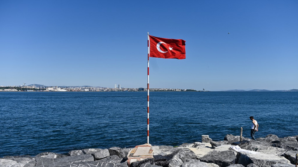 رجل يمشي على الصخور بجانب العلم التركي عند مضيق البوسفور، بعد تفشي مرض فيروس كورونا . 28 يونيو 2020(أوزان كوس / أ ف ب)