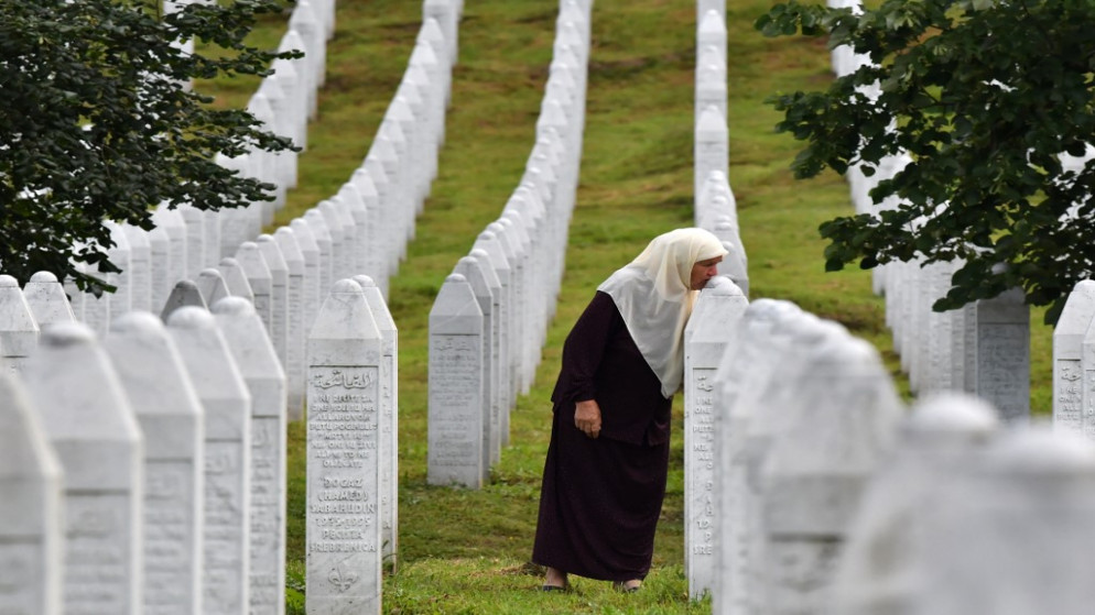 ناجية بوسنية من مذبحة سريبرينيتسا تقبل قبري ابنيها عمر، ومونيب، في المركز التذكاري في بوتوتشاري بعد مقتلهما في المذبحة خلال حرب البوسنة 1992-1995، 2 يوليو/تموز 2020. (أ ف ب)