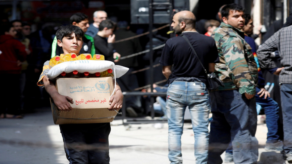 طفل يحمل صندوقا يحتوي مساعدات غذائية استلمه من مركز توزيع مساعدات تابع لبرنامج الغذاء العالمي في حلب السورية. 10/04/2019. (عمر صناديقي / رويترز)