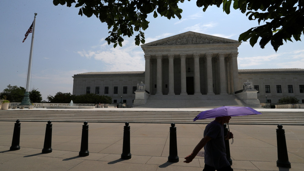 أحد المشاة يحمل مظلة يسير أمام المحكمة العليا للولايات المتحدة في واشنطن. 06/07/2020. (توم برينر/ رويترز)