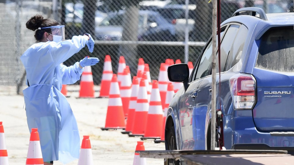 متطوع يرتدي معدات واقية شخصية يوجه تعليمات للسائق في الطابور في موقع اختبار COVID-19، حي مدينة بانوراما في لوس أنجلوس، كاليفورنيا، 30 يوليو 2020. (أ ف ب)