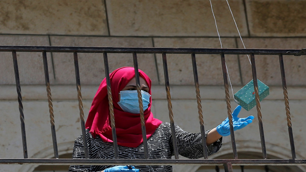 امرأة فلسطينية تتلقى فيتامينات سلمتها طائرة بدون طيار وسط تفشي الفيروس، في بيت أمر في الضفة الغربية المحتلة، 20 يوليو 2020. (رويترز)