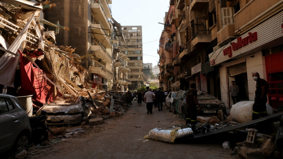 أشخاص يمرون بالقرب من المباني والمركبات المتضررة بعد انفجار الثلاثاء في منطقة المرفأ في بيروت . 5 أغسطس 2020. (رويترز / كارمن يحشوشي)
