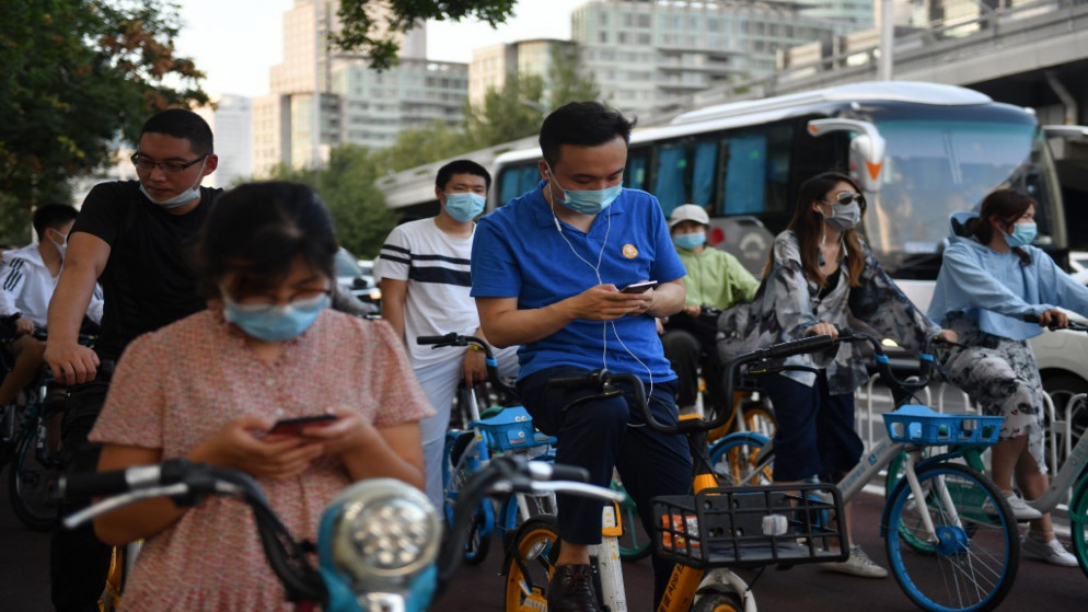 أشخاص يرتدون أقنعة الوجه في ممر للدراجات في بكين . 3 أغسطس 2020. (جريج بيكر / أ ف ب)