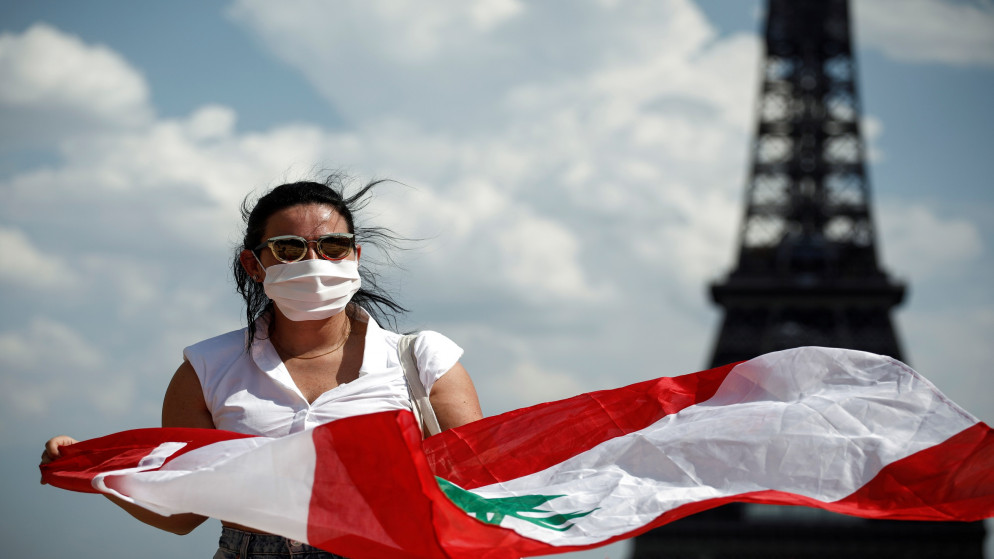 سيدة تحمل العلم اللبناني أثناء تجمع الناس في ساحة بالقرب من برج إيفل في باريس لدعم الشعب اللبناني بعد انفجار بيروت. 09/08/2020. (بينوا تيسييه/ رويترز)