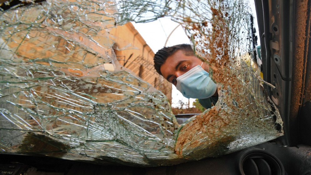 لبناني بالقرب من زجاج مكسور لمركبة بعد انفجار مرفأ بيروت. 11 أغسطس  2020.(أ ف ب)