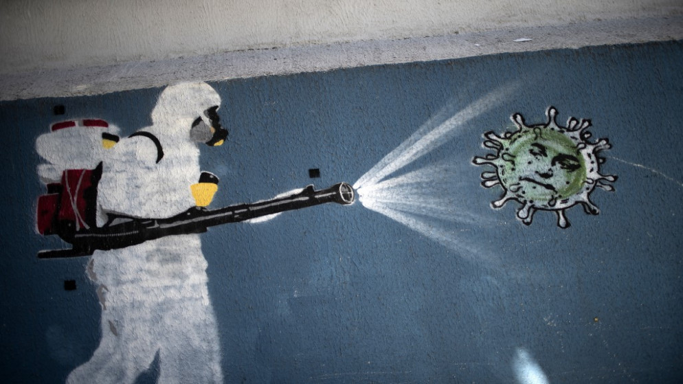 جدارية تصور شخصا يقوم بعملية تعقيم ضد فيروس كورونا في ريو دي جانيرو في البرازيل. (أ ف ب)