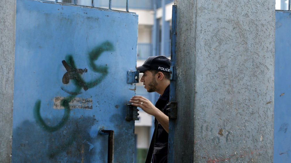 شرطي فلسطيني يقف على مدخل مدرسة تابعة لـ "أونروا" في قطاع غزة، 13 أغسطس 2020.