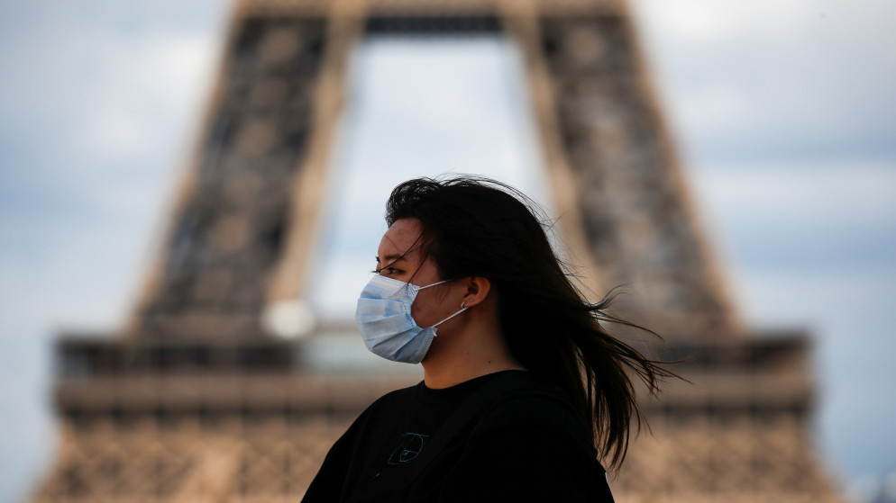امرأة ترتدي كمامة واقية تسير قرب برج إيفل في العاصمة الفرنسية باريس، 3 آب/أغسطس 2020. (رويترز)