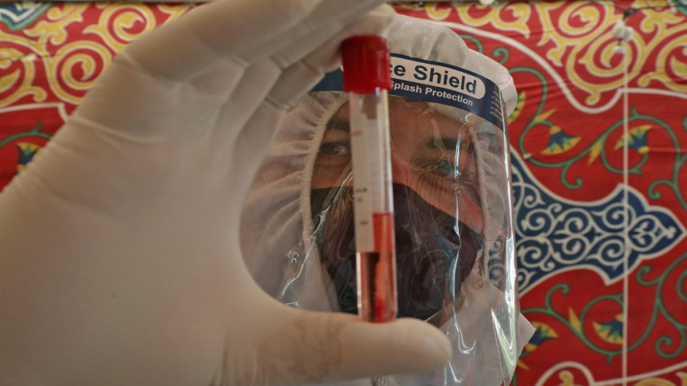 طبيب يعرض عينة دم مأخوذة من شخص يشتبه بإصابته بفيروس كورونا المستجد في الخليل بالضفة الغربية المحتلة. 15 يوليو  2020. (حازم بادر / أ ف ب)