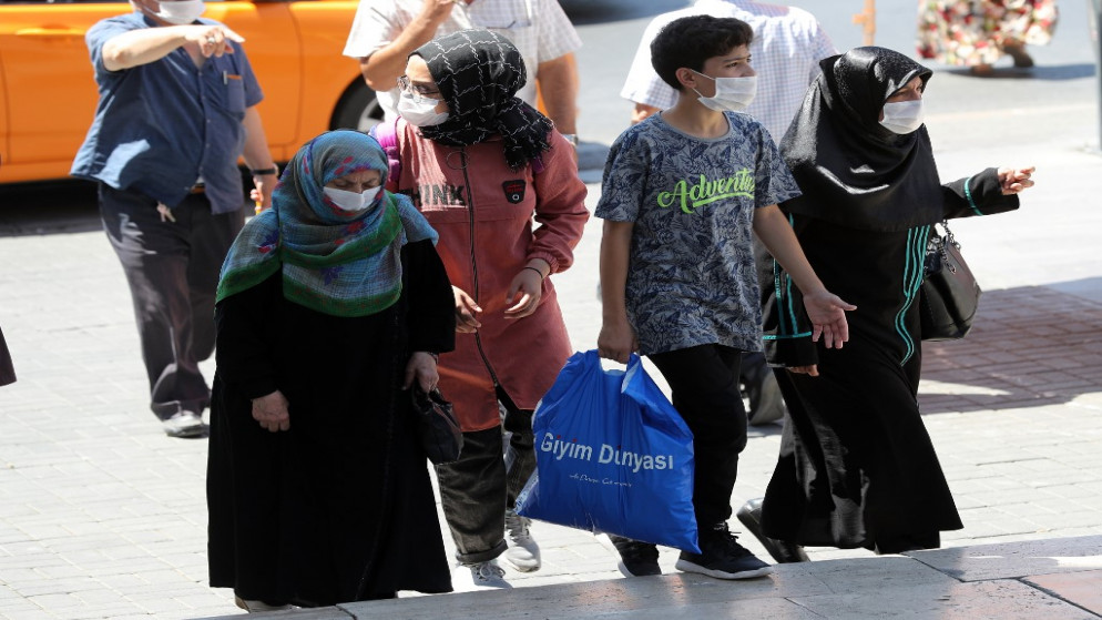 أشخاص يرتدون أقنعة الوجه كإجراء وقائي من فيروس كورونا يسيرون في أحد شوارع منطقة أولوس في أنقرة التركية. 8 أغسطس 2020.(أ ف ب)