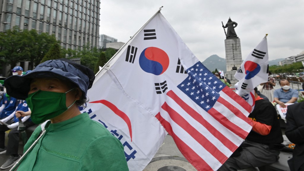 امرأة كورية جنوبية تحمل أعلام كوريا الجنوبية والولايات المتحدة خلال مسيرة للاحتفال بالذكرى 70 لبداية الحرب الكورية في سول .25 يونيو 2020. (أ ف ب)