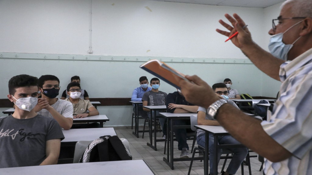 معلم فلسطيني يرتدي "كمامة" خلال إعطاء حصة دراسية بعد إجراءات وقائية وسط وباء كوفيد -19 في مدينة الخليل في الضفة الغربية. 10 أغسطس 2020.(أ ف ب)